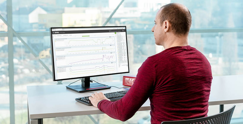 Picture shows a man in a red shirt in front of a monitor with the ENGEL customer portal